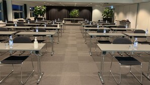 A conference room with rows of tables and chairs, equipped with water bottles and hand sanitizers. - Sportshotel Vejen (Vejen)