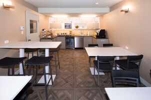 A compact kitchen with modern appliances, a dining area with bar stools, and a herringbone-patterned floor.