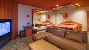 A modern hotel room with a large bed, a sofa, a TV, and a mirror. - Le Chabrol Hotel & Suites (Montreal)