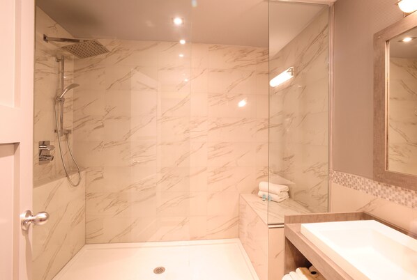 A modern bathroom with a shower, a sink, and a mirror. - Le Chabrol Hotel & Suites (Montreal)
