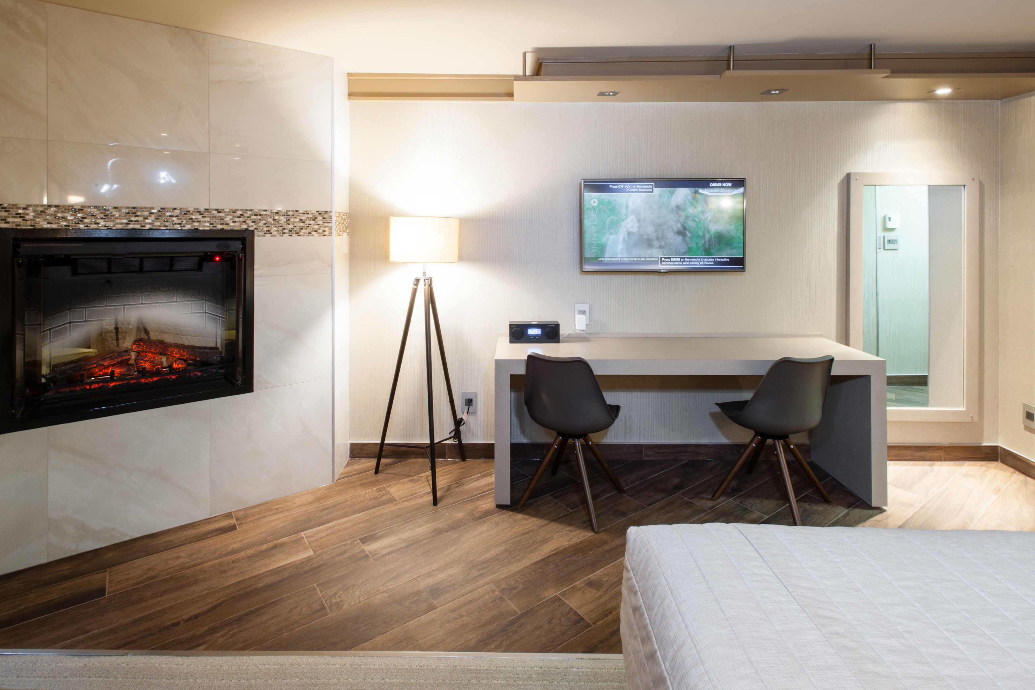 Una habitación de hotel con chimenea, un escritorio con dos sillas, televisión y una cama.