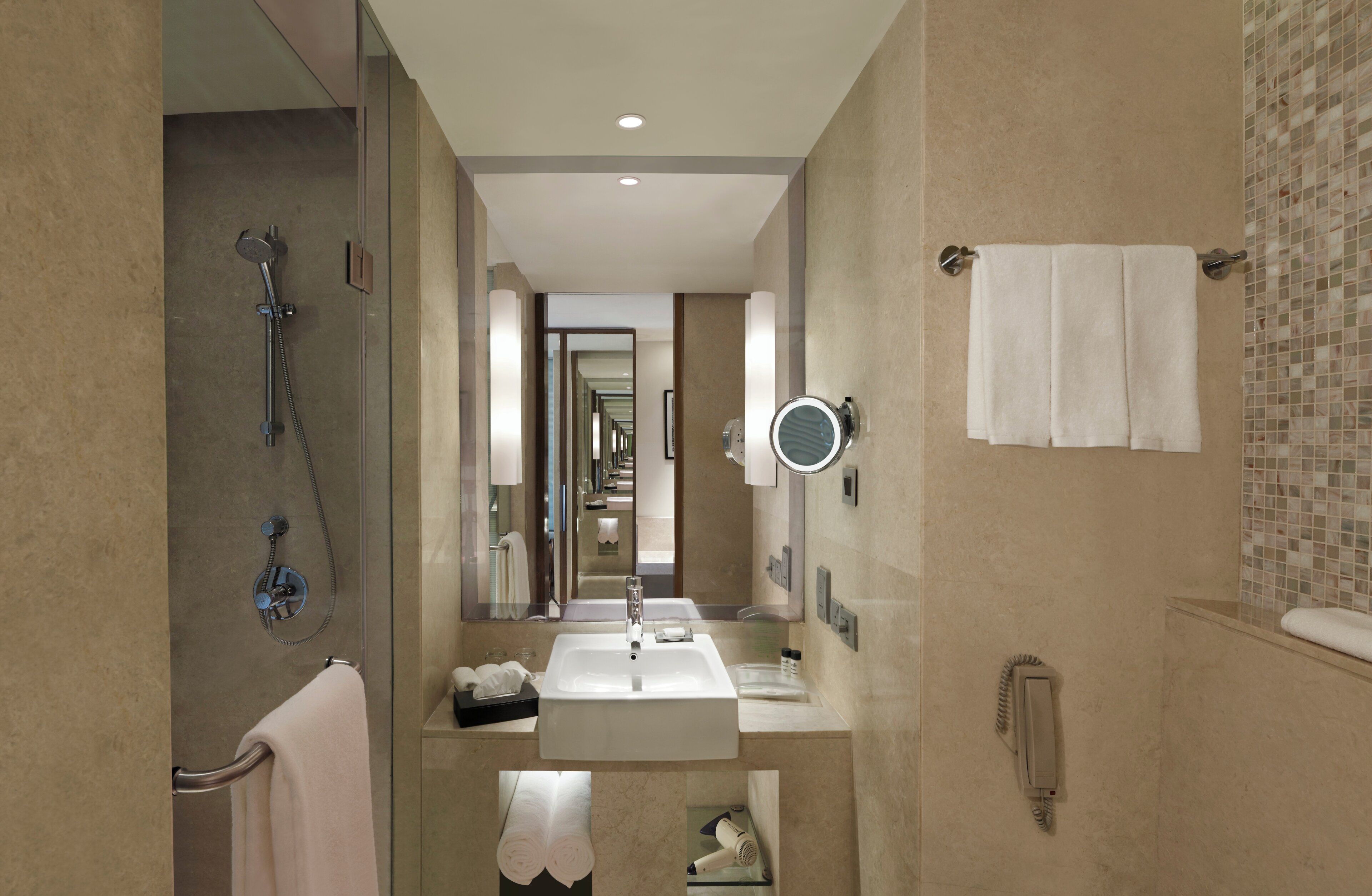A modern bathroom with a walk-in shower, a large mirror, a sink, and a towel rack.