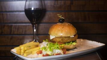 Une assiette avec un hamburger, des frites et un verre de vin rouge.