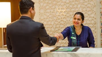 Una reception con un piano in marmo e una parete alle spalle decorata con un motivo geometrico.