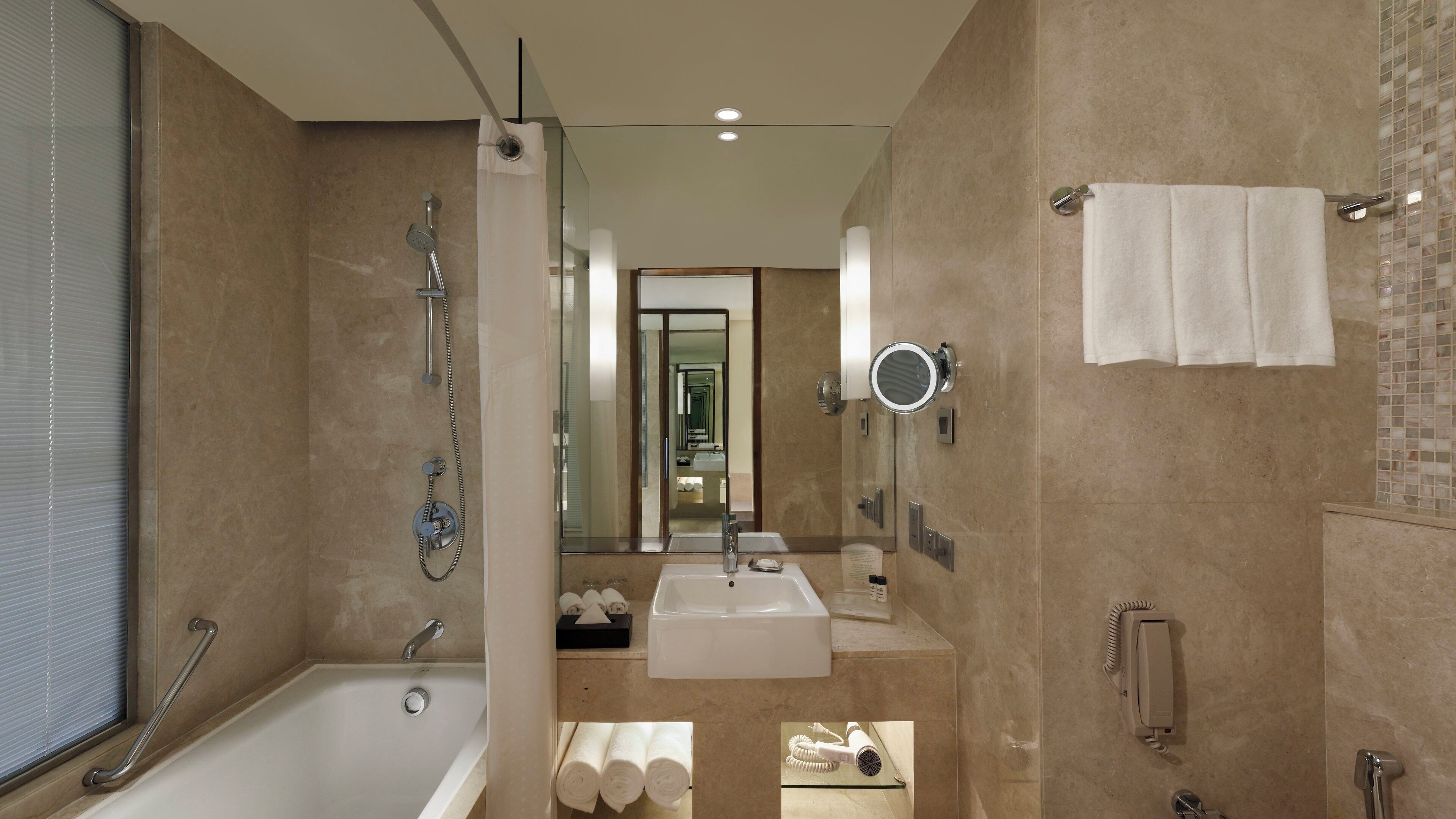 A modern bathroom with a bathtub, a shower, a sink, and a mirror.