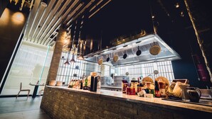 Une cuisine moderne avec un comptoir en briques, des ustensiles de cuisine suspendus et une grande fenêtre.