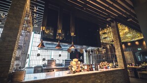 Une cuisine moderne aux éléments de design industriel, notamment des murs en briques apparentes, des garde-corps en métal et des luminaires suspendus.