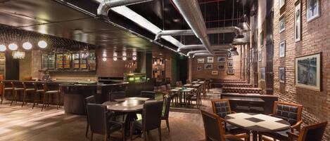 A restaurant with brick walls, exposed ductwork, and a bar area with stools and tables.