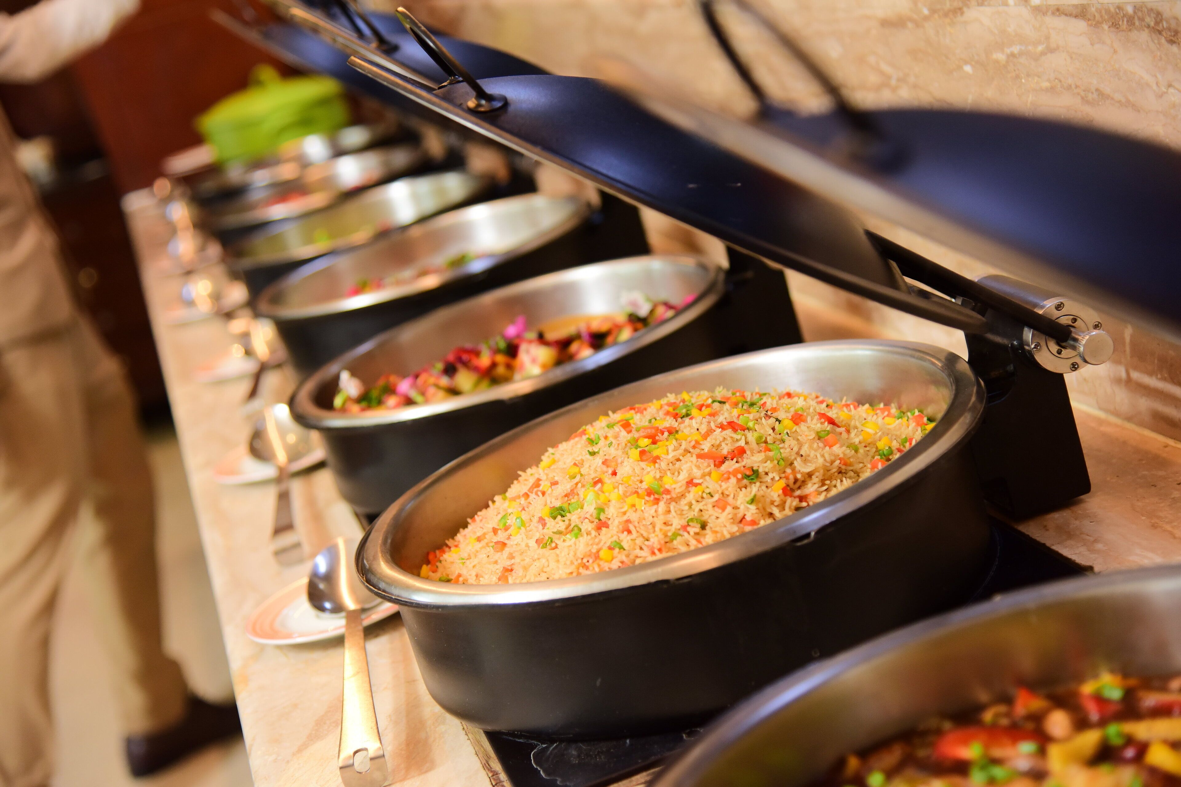 A buffet with multiple serving dishes containing various dishes, including rice and vegetables.