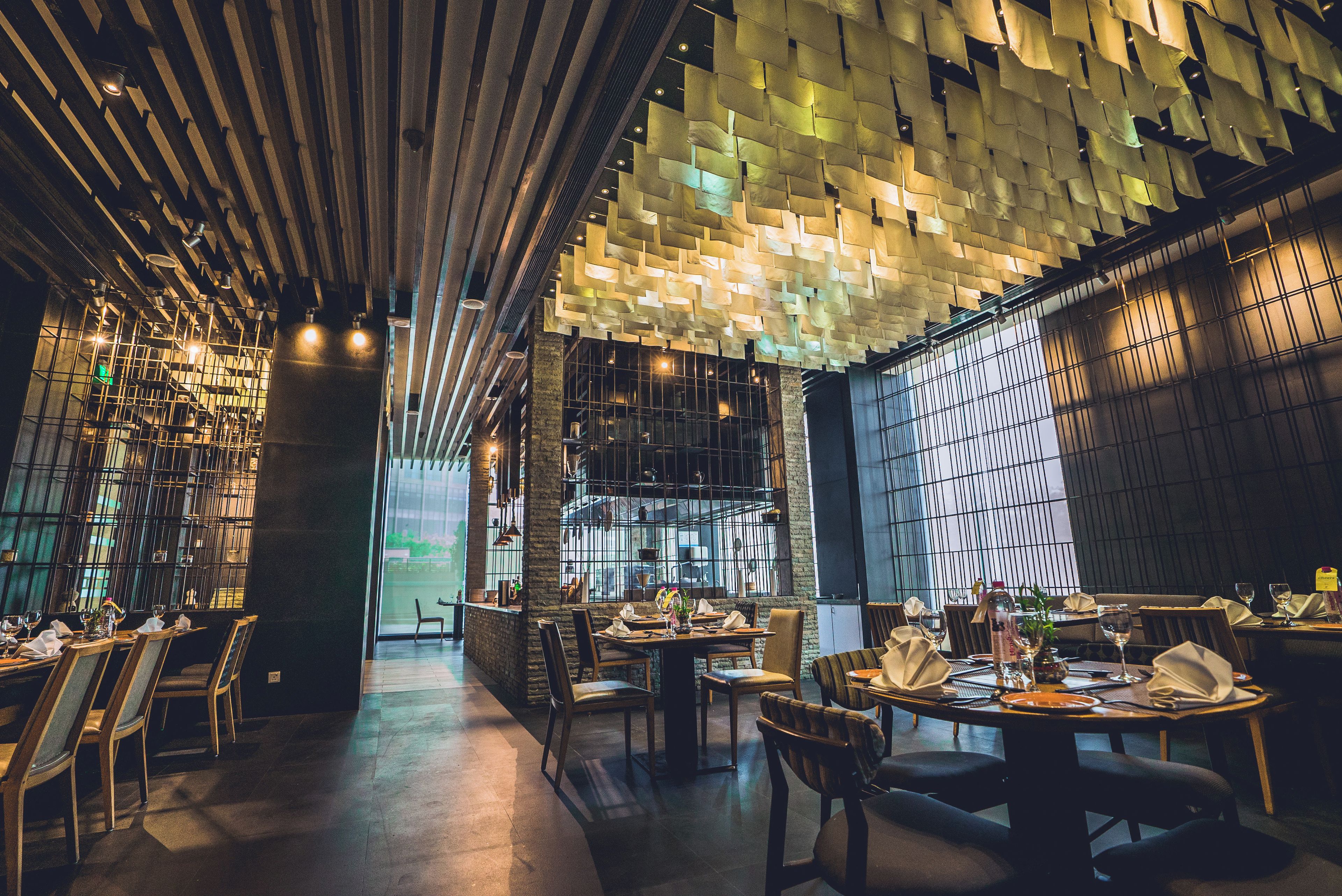 Interior de restaurante con diseño moderno, destacando un patrón único en el techo, mesas y sillas de madera.