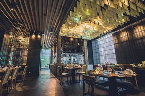 L’intérieur d’un restaurant au design moderne, avec un motif original au plafond, des tables et des chaises en bois.