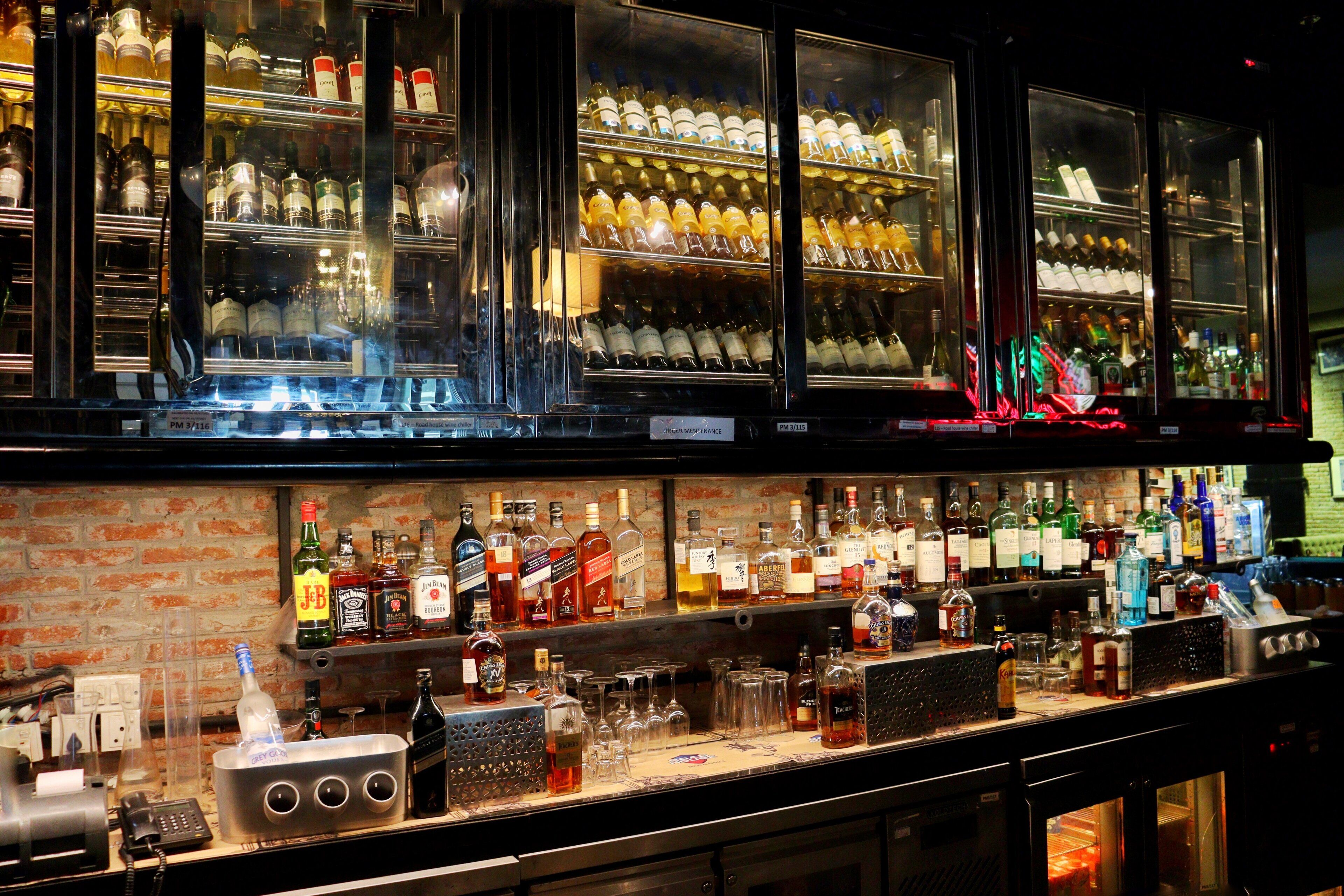 Eine Bar mit Regalen voller Spirituosenflaschen, Gläsern und einer Kasse.