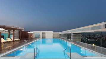 A swimming pool with lounge chairs and a covered seating area.