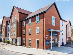 A Travelodge hotel with a brick facade, multiple windows, and a visible entrance. - Travelodge Chertsey (Chertsey)