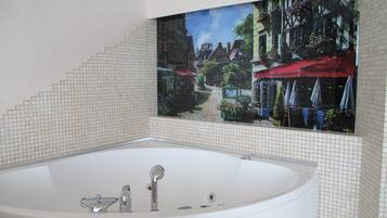 Une salle de bain avec une grande baignoire, des murs carrelés et une fresque représentant une scène de rue.