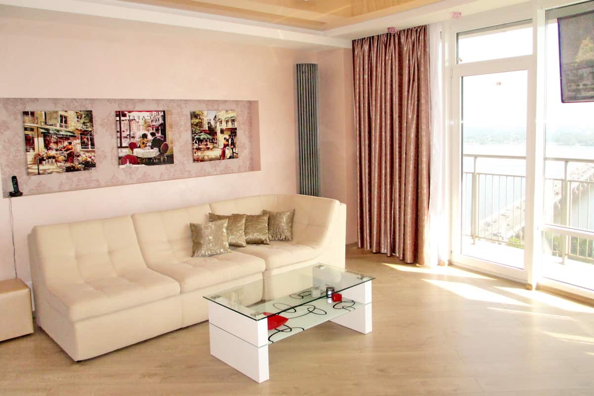 A modern living room with a beige sofa, a glass coffee table, and three framed pictures on the wall.