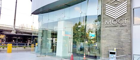 A modern building with a glass facade, a metal railing, and a sign reading "MOCT".