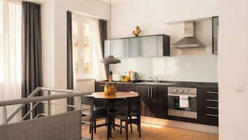 A modern kitchen with dark cabinetry, a stainless steel stove, and a dining area with a table and chairs.