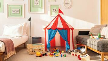 A child's play area with a small tent, toys, and framed pictures on the wall.