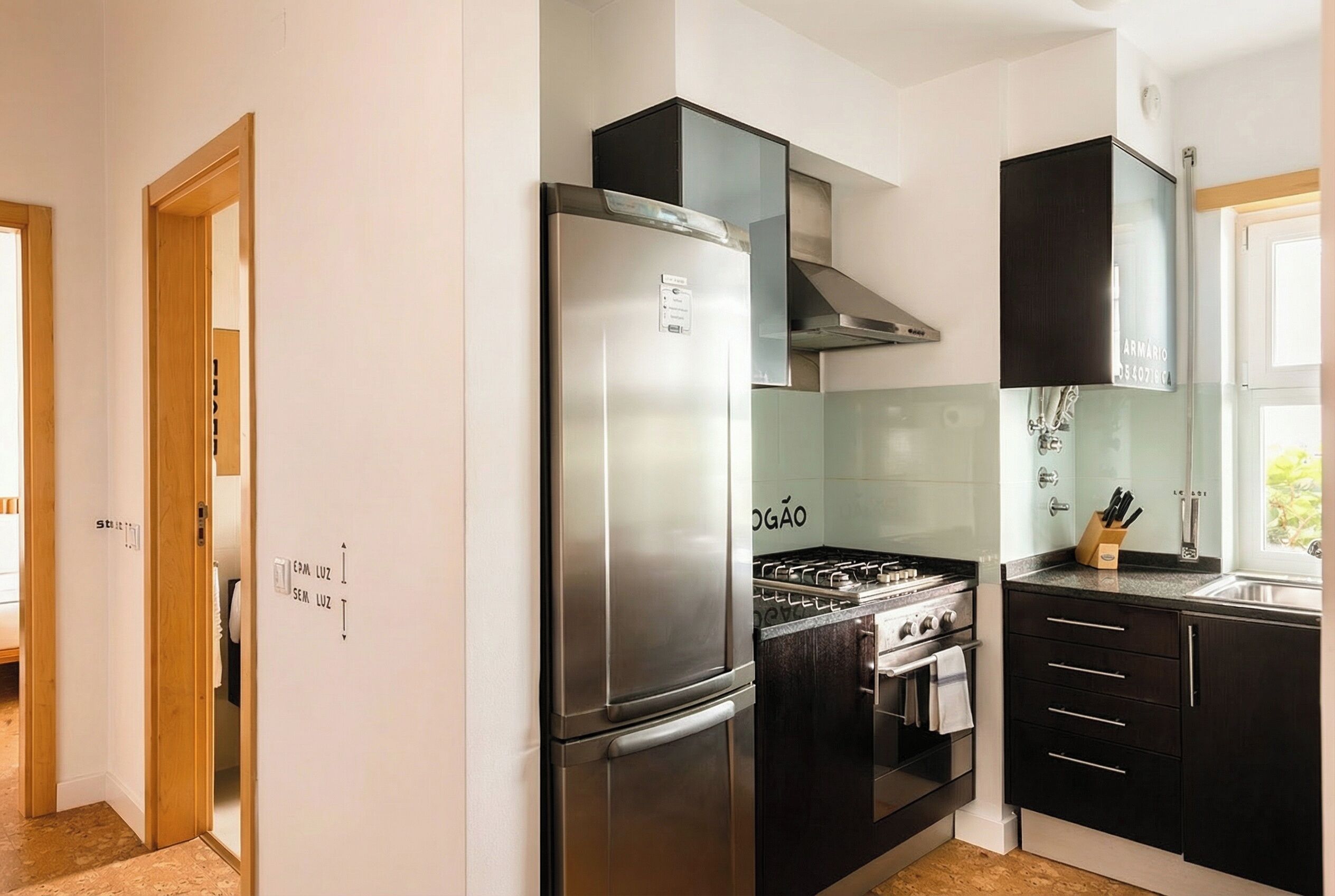 Una cocina moderna con un refrigerador de acero inoxidable, una estufa a gas y gabinetes negros.