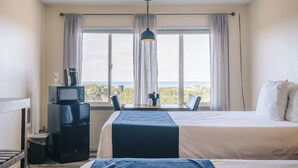 Habitación de hotel con una cama, un escritorio con computadora, un microondas y un cesto de basura.