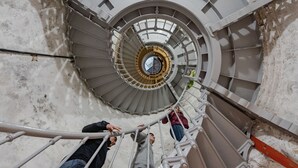 Una escalera de caracol con barandillas de metal y un pilar central.