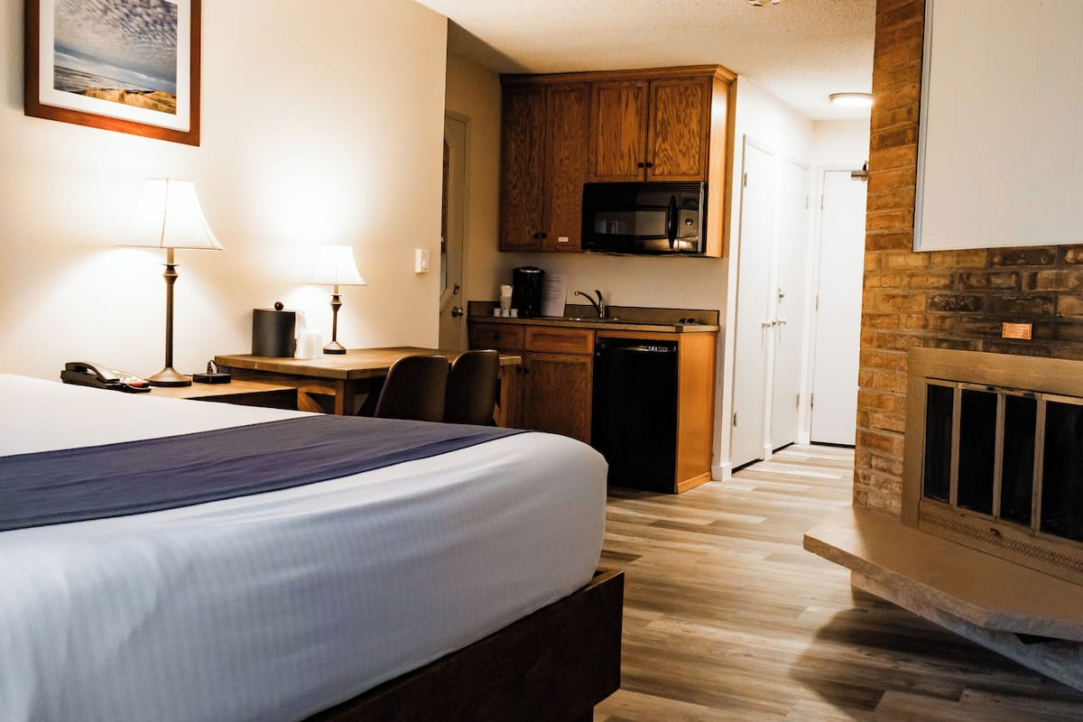 A hotel room with a bed, desk, and kitchenette.