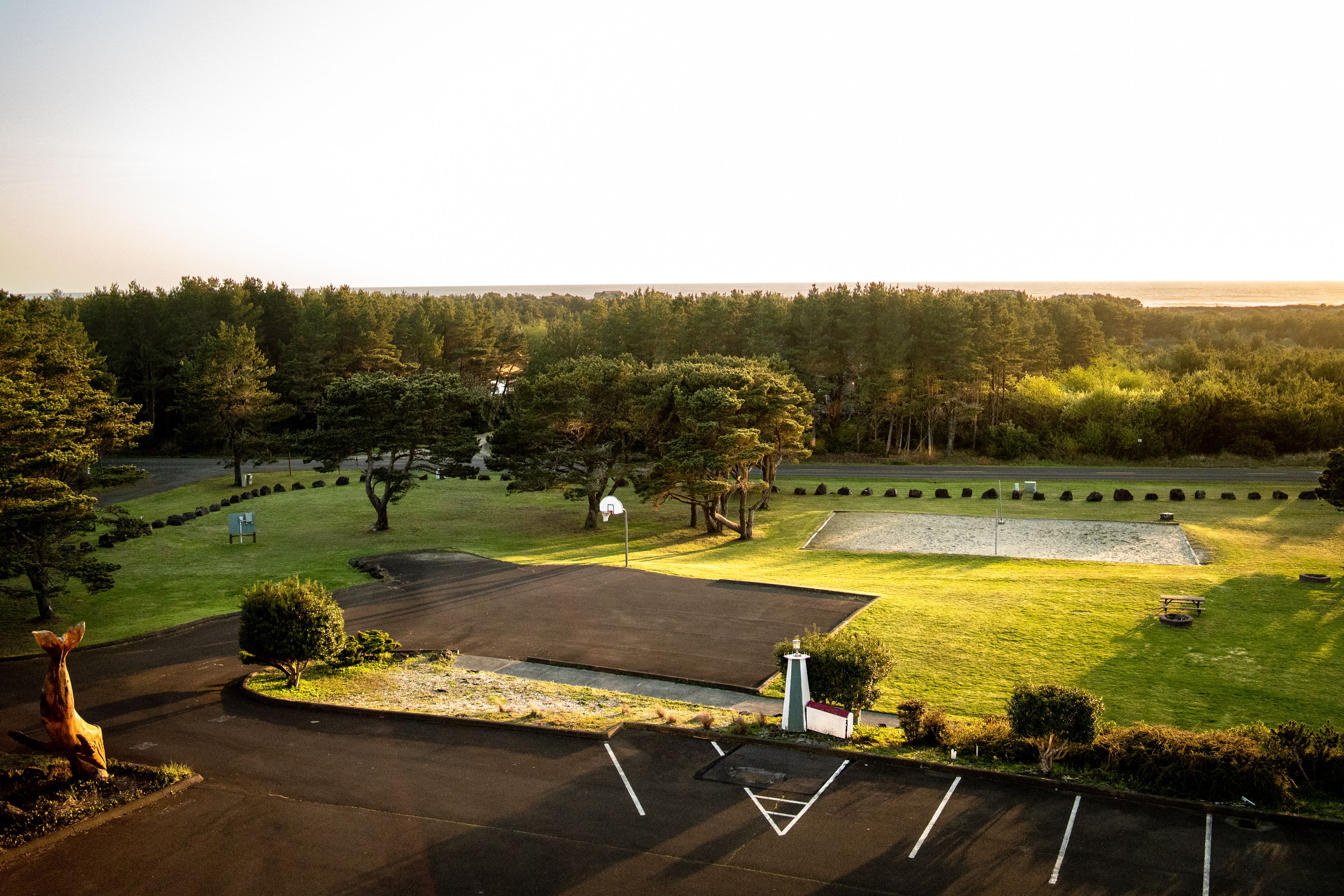 A parking lot with basketball courts, surrounded by trees and a grassy area.
