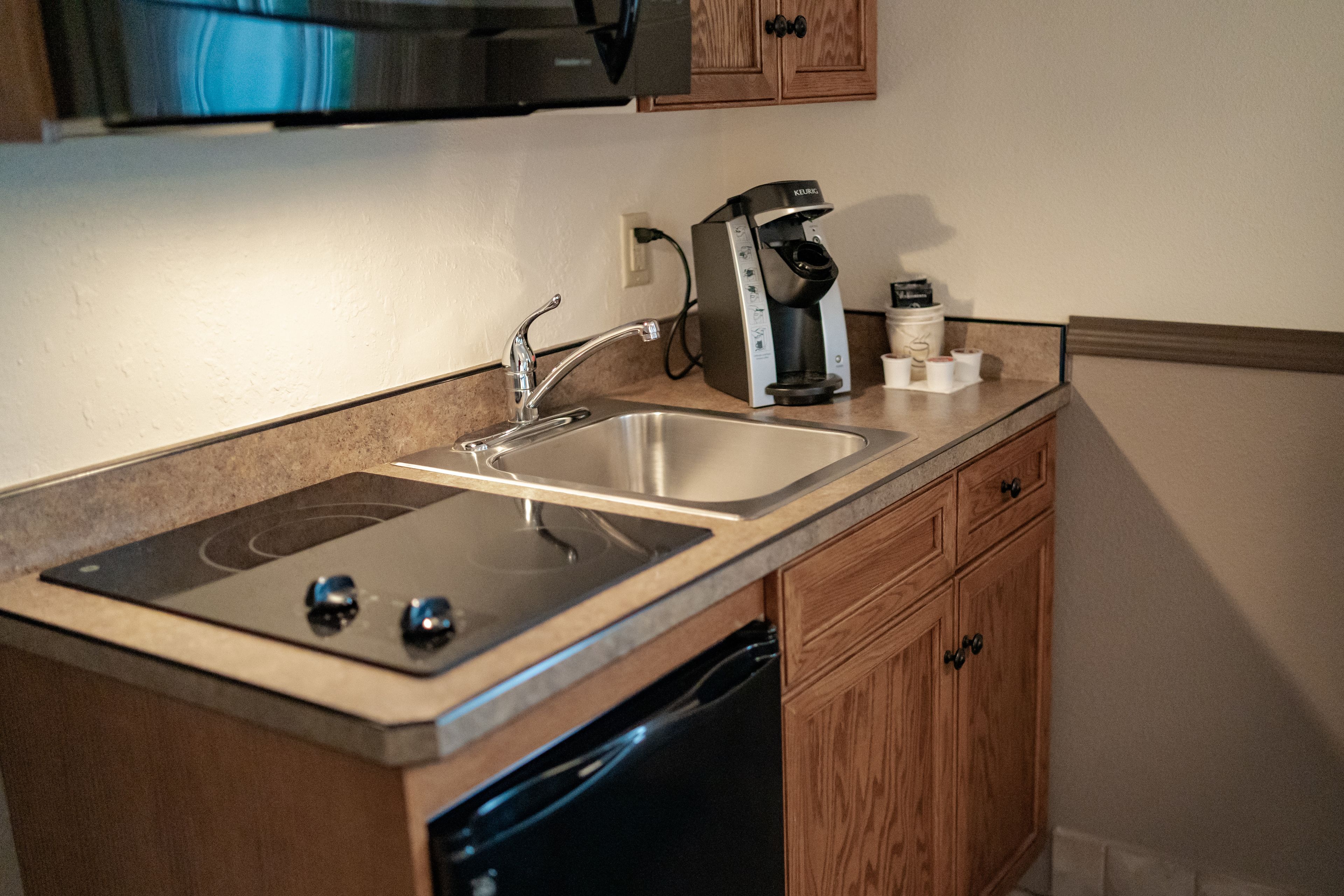 A compact kitchen with a built-in dishwasher, a coffee maker, and wooden cabinets.