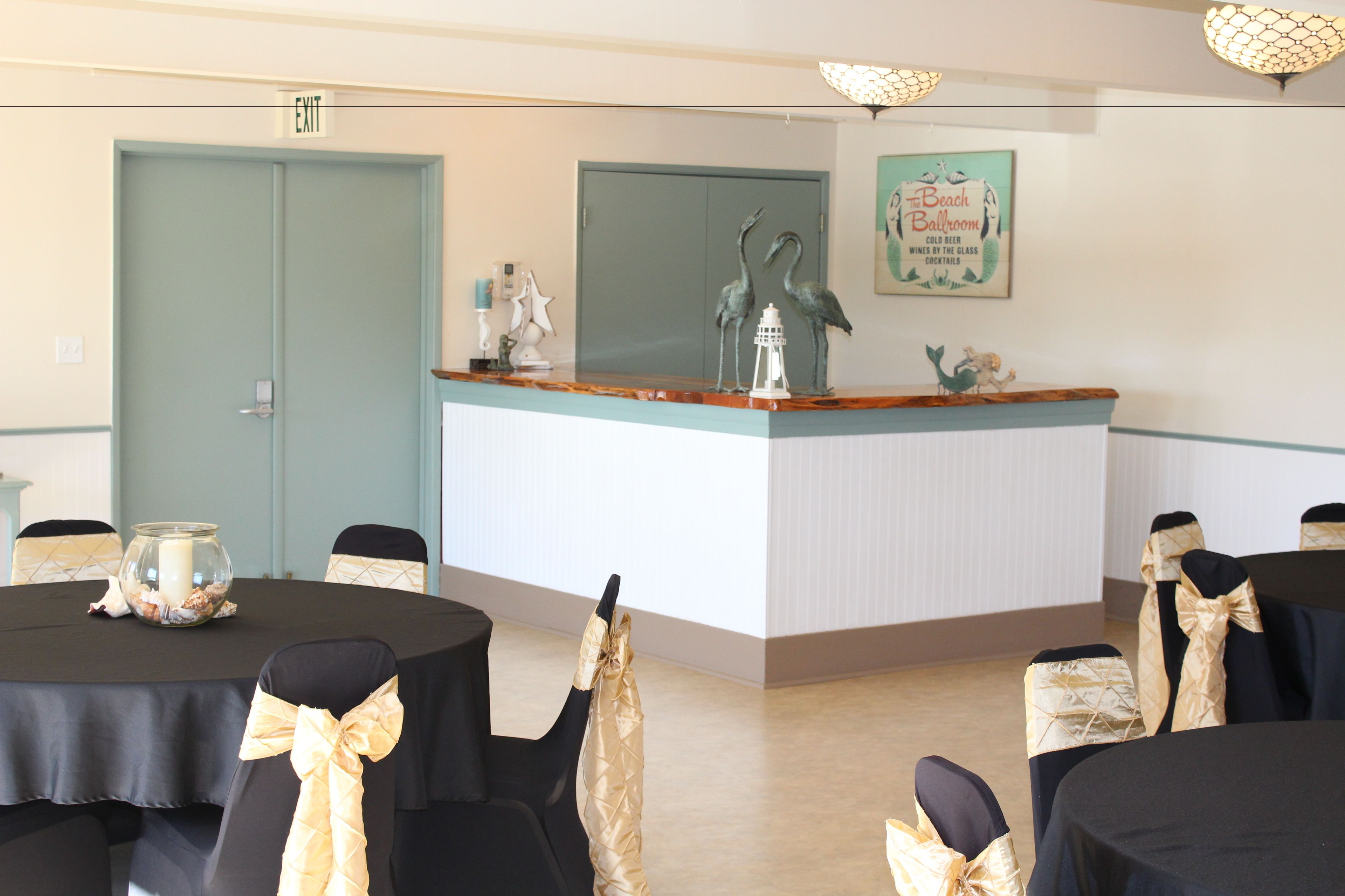 A conference room with a reception desk, chairs with gold sashes, a framed sign on the wall, and a door labeled "EXIT".