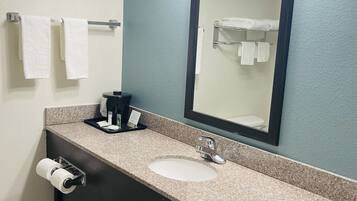A bathroom with a granite countertop, a sink, a mirror, and a towel rack.