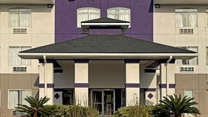 A Sleep Inn & Suites by Choice Hotels building with a purple facade, a flat roof, and a central entrance. - Sleep Inn & Suites Foley - Gulf Shores North (Foley)