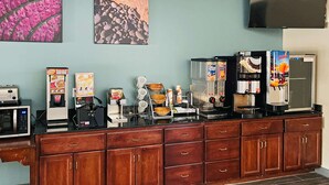 A coffee station with various machines, a microwave, and a TV mounted on the wall. - Sleep Inn & Suites Foley - Gulf Shores North (Foley)