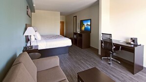 A hotel room with a bed, a desk, a chair, a sofa, a TV, and a coffee maker. - Sleep Inn & Suites Foley - Gulf Shores North (Foley)