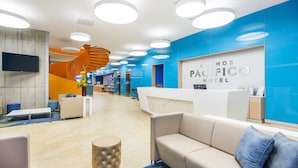 A hotel reception area with a modern design, including a curved reception desk, seating area, and a spiral staircase. - Cosmos Pacifico Hotel (Buenaventura)