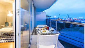 A balcony with a dining table set for breakfast, overlooking a harbor with cranes and ships. - Cosmos Pacifico Hotel (Buenaventura)
