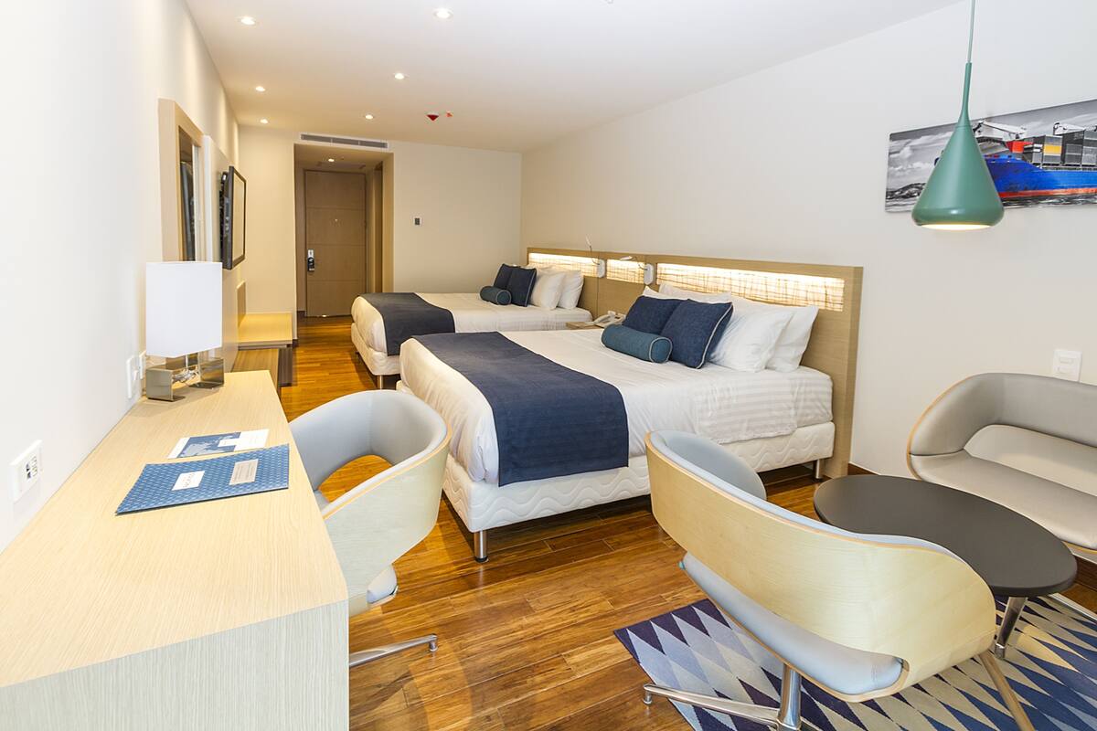 Een hotelkamer met twee bedden, een bureau, een stoel, een badkuip en een douche.