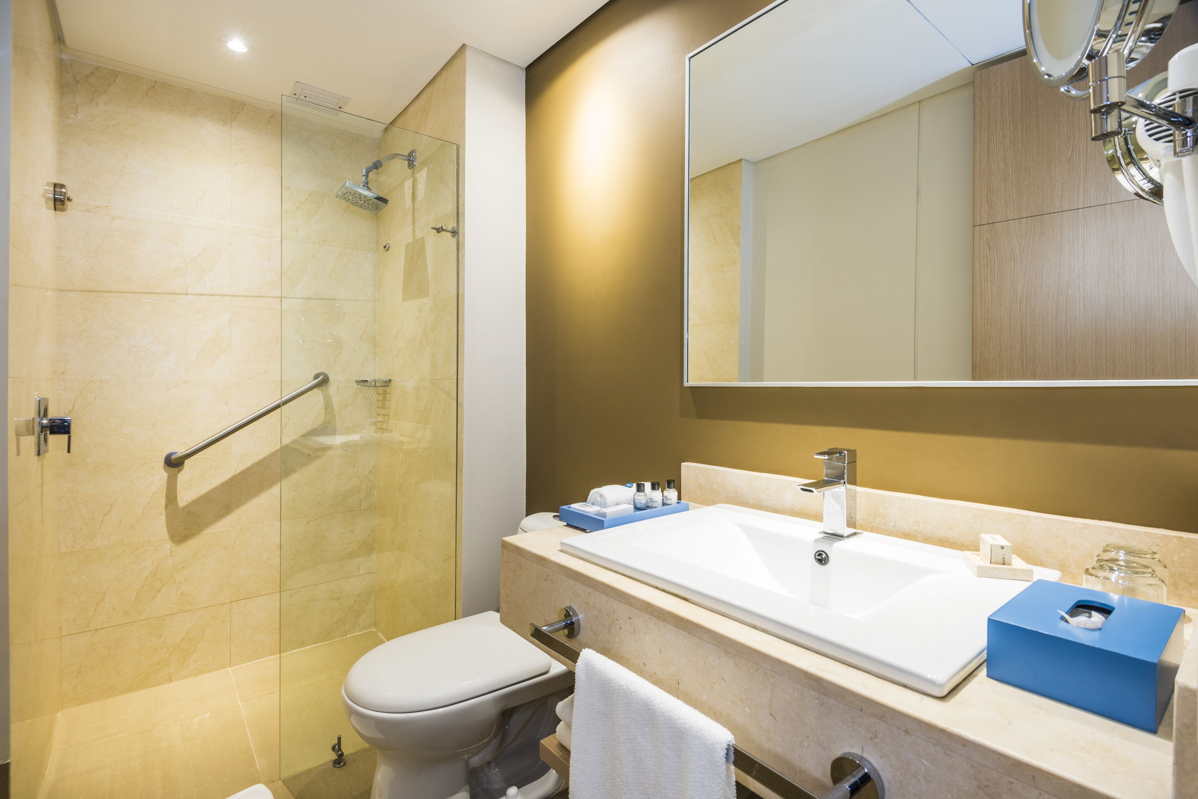 Un baño moderno con cabina de ducha de vidrio, un lavabo blanco y un espejo grande.