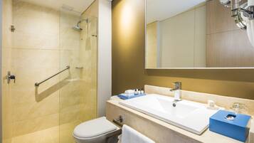 Un baño moderno con cabina de ducha de vidrio, un lavabo blanco y un espejo grande.