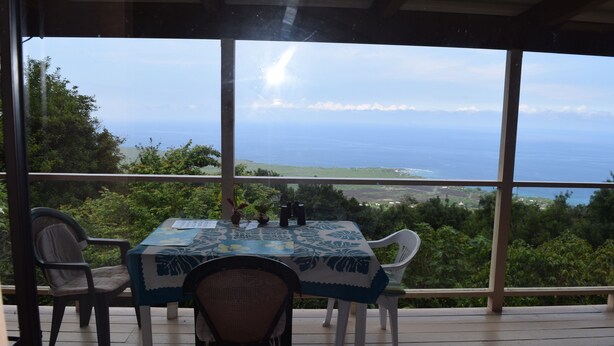 A table with a blue tablecloth on a wooden deck overlooking a scenic view. - A Beautiful Edge of the World B&B (Captain Cook)