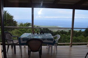 Une table recouverte d’une nappe bleue, placée sur une terrasse en bois offrant une vue panoramique.