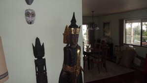 A room with a statue, a dining area, and a window with a view. - A Beautiful Edge of the World B&B (Captain Cook)