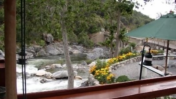 A view from a balcony overlooking a river with rocks and greenery. - The Gateway Restaurant & Lodge (Three Rivers)