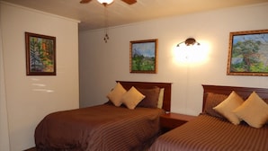 A hotel room with two beds, a ceiling fan, and wall-mounted artwork. - The Gateway Restaurant & Lodge (Three Rivers)