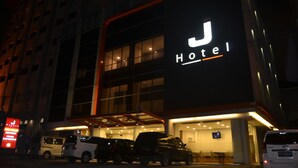 Un hotel con un letrero iluminado llamativo, amplias ventanas y un área de acceso cubierta.