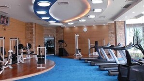 Un gimnasio con cintas de correr, máquinas de pesas y alfombra azul.