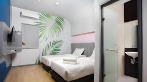 Una habitación de hotel moderna con dos camas, un televisor de pantalla plana, aire acondicionado instalado en la pared y un baño con lavamanos y espejo.
