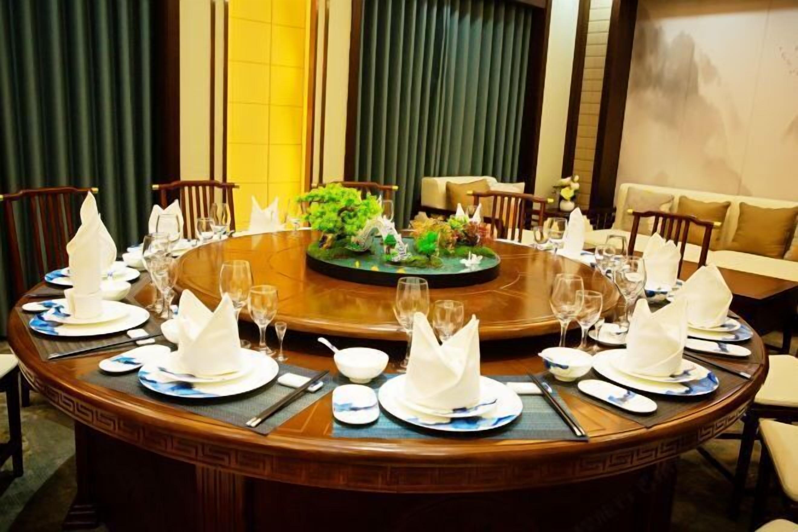 A round dining table set for a formal meal with white napkins, blue and white plates, and clear glasses.