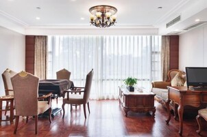 Amplia sala de estar con un ventanal grande, una araña, muebles de madera y un televisor.