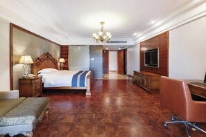 A hotel room with a large bed, a desk, a television, and a chandelier. - Pingye Garden Hotel (Liangping)